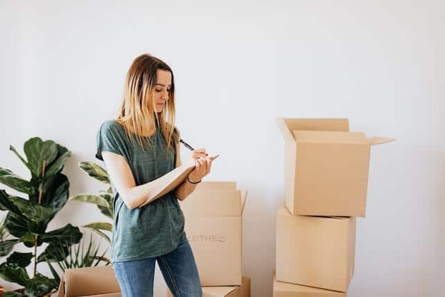 A woman standing near cardboard boxes.