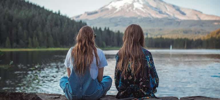 two women sitting on the lake shore and talking